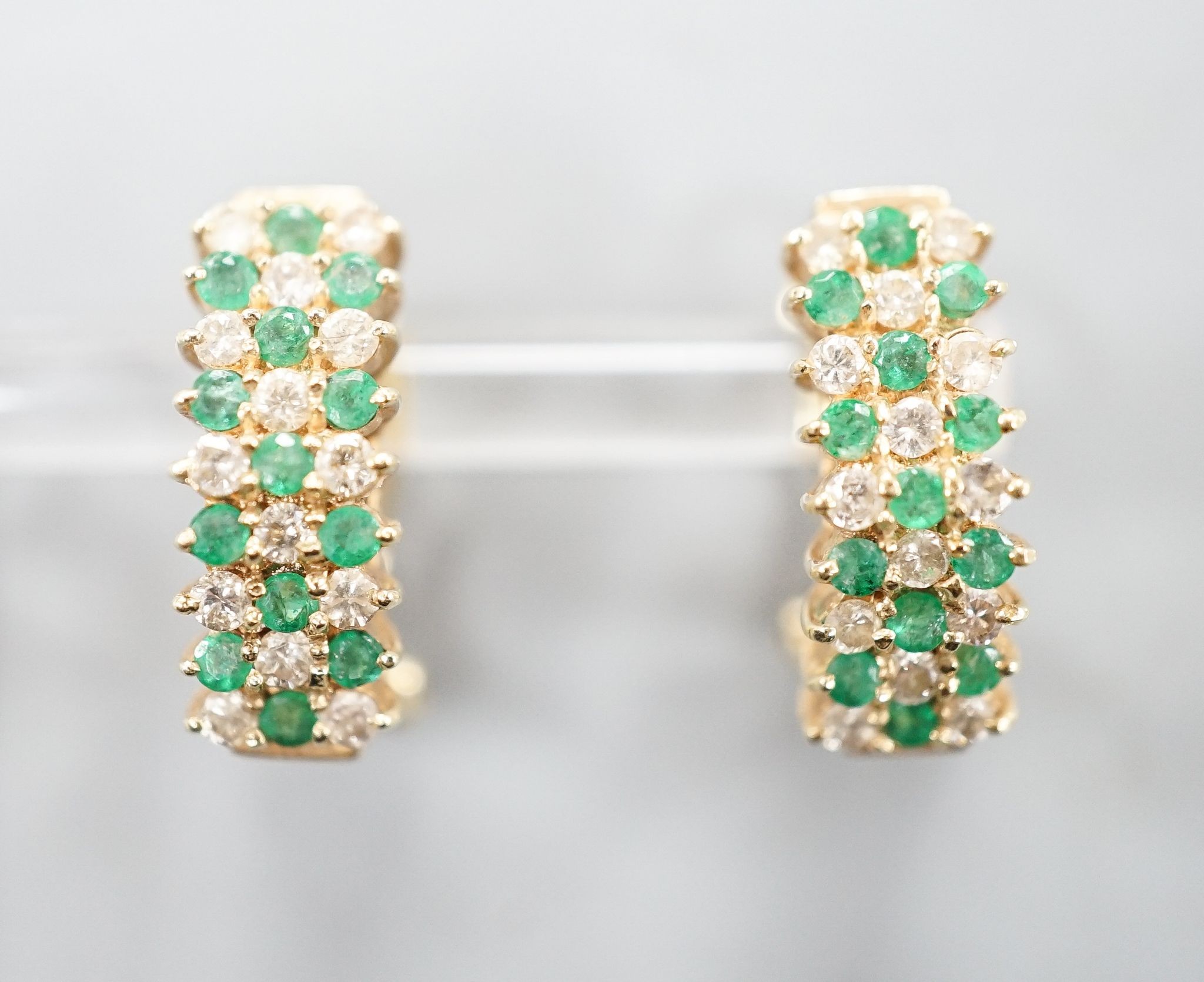 A pair of 14k yellow metal, emerald and diamond set curved earrings, 19mm, gross weight 7.4 grams.